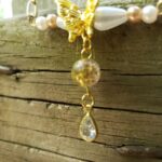 Dainty drop necklace featuring a brilliant crystal butterfly pendant, featuring sparkle and a modern minimalist design Close-up of a silver bar necklace with a small crystal butterfly drop, worn against a neutral background